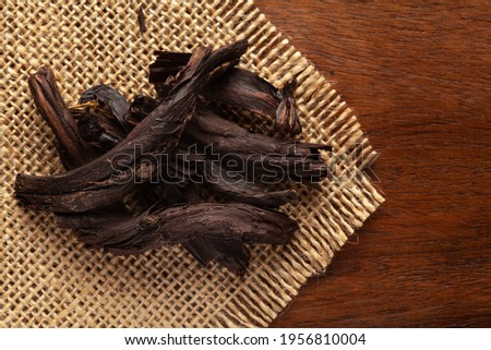 Macro close-up of Organic Alkanna tinctoria or ratan jot on the wooden top background and jute mat. Pile of Indian Aromatic Spice. Top view