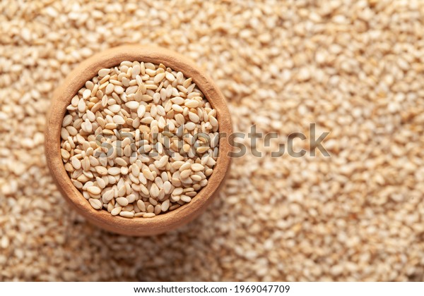 Macro Close-up of Organic White Sesame\
seeds(Sesamum indicum) or white Til in an earthen clay pot (kulhar)\
on the self background. Top\
view\
