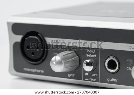 Macro close-up of professional audio interface controls and silver knobs, focus on gain settings and instrument inputs for studio recording and music production.