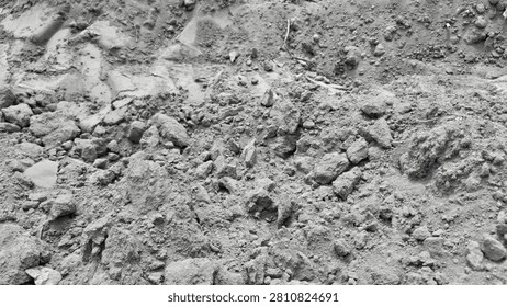 . A macro close-up of rough, clumpy soil mixed with small rocks and gravel, highlighting the uneven, raw texture of a dry, uncultivated natural ground surface.
