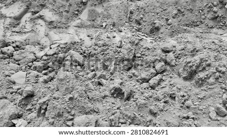 . A macro close-up of rough, clumpy soil mixed with small rocks and gravel, highlighting the uneven, raw texture of a dry, uncultivated natural ground surface.
