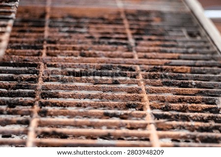 macro closeup of a rusty and weathered bbq grill in need of cleaning. summer background.