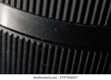 Macro closeup selective focus of a ridged black camera lens barrel's extreme detail, showcasing fine texture with a pleasing bokeh blur for microstock.