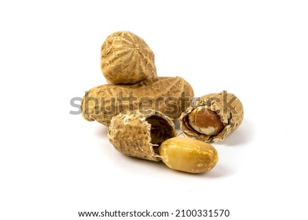 a macro closeup of several roasted peanuts in the shell and one peanut broken in half isolated on white