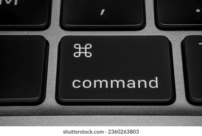 Macro close-up shot of a command button on a black keyboard on silver metallic background.