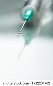 Macro closeup shot of medical needle tip,green syringe isolated on white background with reflection,healthcare concept,vaccination  immunization illustration,global Coronavirus COVID-19 pandemic cure