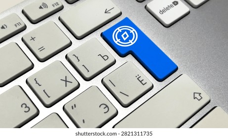 Macro close-up of a silver computer keyboard featuring a custom blue Enter key printed with a white icon of a target reticle containing a diamond shape, representing precision, focus, aiming, and goal setting.