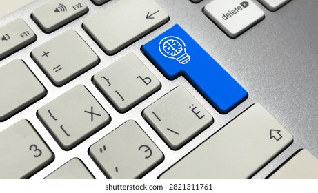 Macro close-up of a silver computer keyboard featuring a custom blue Enter key printed with a white line-art icon of a lightbulb containing a human brain, symbolizing ideas, intelligence, and innovation.
