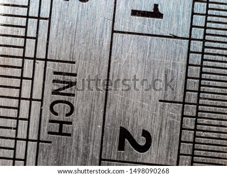 Macro close-up of a stainless steel ruler with british and metric system measuring scales: Inches and millimeters.
