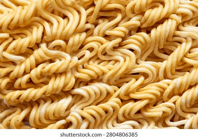 Macro Close-up Texture of Dried Instant Noodles,A detailed close-up, top-down view of dried, wavy instant noodle strands creating a repetitive geometric texture and abstract pattern, highlighting the golden-yellow surface and intricate shapes of dry wheat noodle food product.