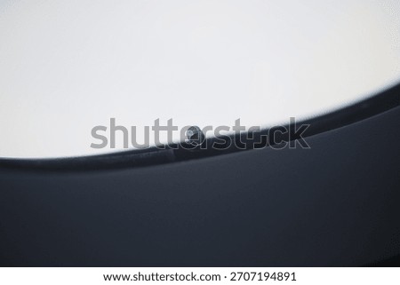 Macro close-up of the tiny breather hole in an airplane window.