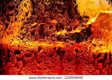 macro cola drink background,Close up view of ice cubes in dark cola background. Surface of sweet summer cold drink with foam and macro bubbles on glass wall. Fizzing or float to the top of the surface