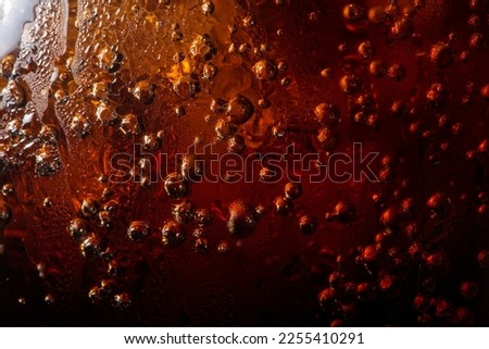macro cola drink texture,macro soft drink texture,Close up view of ice cubes in dark cola background. Textures of sweet summer cold drinks with foam and macro bubbles on Fizzing glass wall.