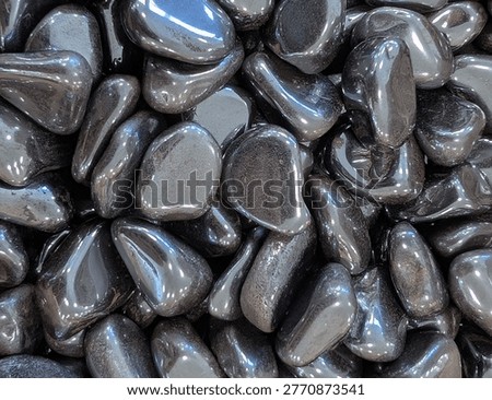 Macro composition of lustrous, metallic grey tumbled hematite stones with strong highlights.
