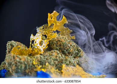 Macro detail of cannabis nugs and marijuana concentrates (aka shatter) with smoke isolated over black