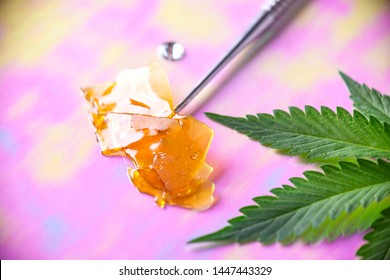 Macro detail of dab tool with cannabis concentrate aka shatter and marijuana leaf, cannabis extraction concept