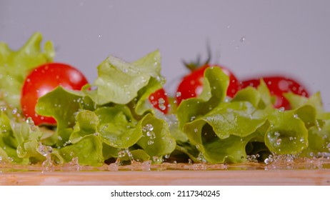 MACRO, DOF: Bright Red Tomatoes Fall And Land Onto The Wet Romaine Lettuce Leaves Sitting On The Cutting Board. Detailed View Of Ripe Cherry Tomatoes Falling Onto The Cluttered Chef's Chopping Board.