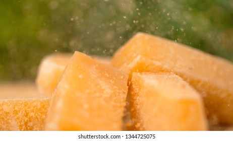 MACRO, DOF: Delicious Parmesan Flakes Fall On The Cheese Cubes On The Wooden Board. Mouth-watering Shot Of Yellow Parmesan Cheese Being Grated Over The Whole Cheese Cubes. Gourmet Delicacy From Italy.