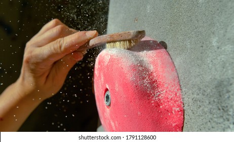 MACRO, DOF: Female climber uses a brush with rough bristles to get rid of magnesium stuck to a pink crimp. Unrecognizable rock climber cleans up a pink crimp hold with a firm brush. Gym maintenance. - Powered by Shutterstock