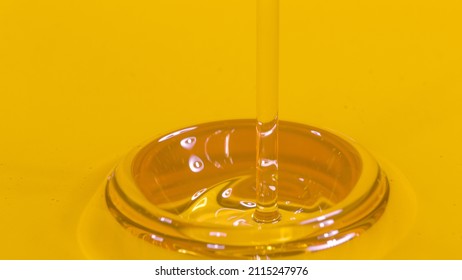 MACRO, DOF: Viscous Golden Almond Oil Gets Poured Into A Transparent Container. Shiny Unrefined Organic Flaxseed Oil Flows Into A Barrel Filled With The Liquid. Natural Hair And Body Care Product.