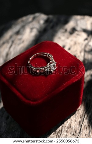 Macro focus of a gold diamond ring and red velvet jewelry box in the backyard in the morning.