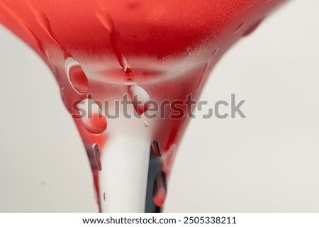 macro frame of glasses with cool red cocktail ice cubes condensation and drops on the glass fruity red balls