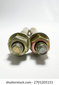 A macro front-view of the large hex nuts and washers on two yellow zinc-plated anchor bolts, emphasizing the shiny metallic finish