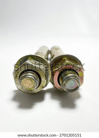 A macro front-view of the large hex nuts and washers on two yellow zinc-plated anchor bolts, emphasizing the shiny metallic finish