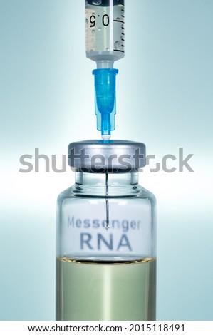 Macro of a hypodermic syringe or needle being filled with mRNA vaccine from bottle against a blue background