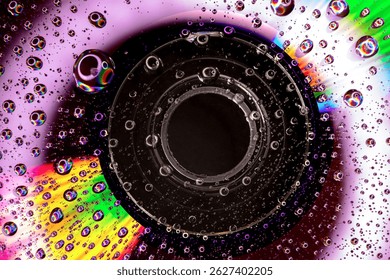 Macro image of a Compact Cisc (CD) with water droplets on its Surface with lighting that creates Multicolored Reflections and a Psychedelic Look.  Retro Aesthetic of 1980s and 1990s, evoking Nostalgia