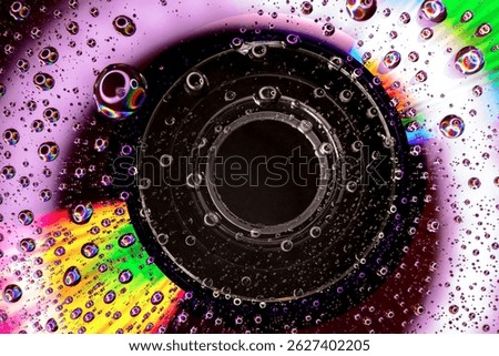 Macro image of a Compact Cisc (CD) with water droplets on its Surface with lighting that creates Multicolored Reflections and a Psychedelic Look.  Retro Aesthetic of 1980s and 1990s, evoking Nostalgia