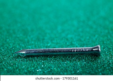 A macro image of enforced concrete nail on a green sandpaper - Shutterstock ID 179301161