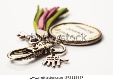 Macro of keychain made with antique gold and leather straps isolated on white background. Handmade jewelry.