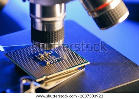 Macro Microprocessor positioned beneath microscope on metal stage.