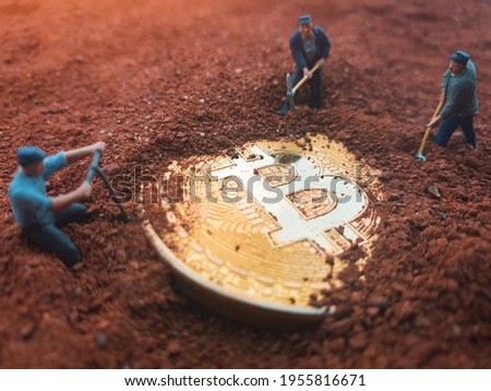 Macro miner figurines digging ground to uncover big shiny bitcoin. Cryptocurrency, blockchain, mining, Fomo or trading concept.