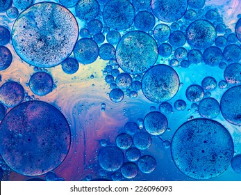 macro of oil drops and pigment on water surface with bright background