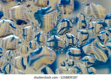 Macro photo. Abstract aqua pattern as background. Twisted reflections in water droplets. Blue lines and multi-story building.