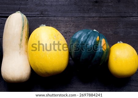 Macro photo of assorted winter squash — butternut, spaghetti, and acorn — arranged on dark rustic wood, ideal for seasonal produce and farm-to-table themes.