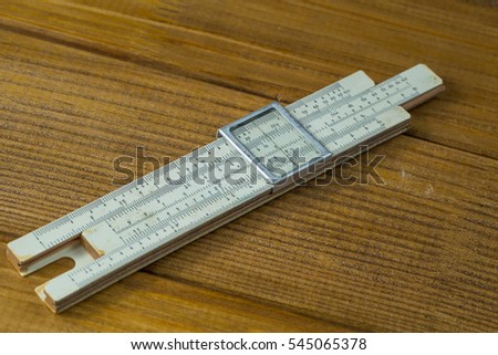 Macro photo, close-up range high-precision hand-held calculating tools - logarithmic ruler  brown wooden background