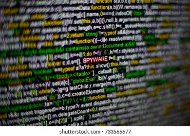 Macro photo of computer screen with program source code and highlighted SPYWARE inscription in the middle. Script on the screen with virus in it. Cyber security concept. Technology background.