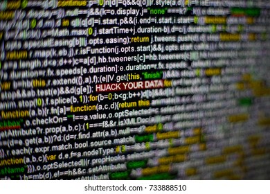 Macro photo of computer screen with program source code and highlighted HIJACK YOUR DATA inscription in the middle. Script on the screen with virus in it. Cyber security concept. Technology background