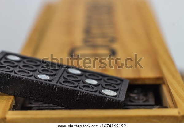 Macro photo of the dominoes game wooden box with\
black rectangular tiles inside with a line dividing its face into\
two square ends.