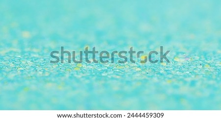 Macro photo of glitter paper. Green background with a thin focal part and a main part in defocus.