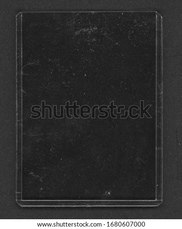macro photo of plastic trading card sleeve on black paper background with dust, collector's plastic holder isolated.