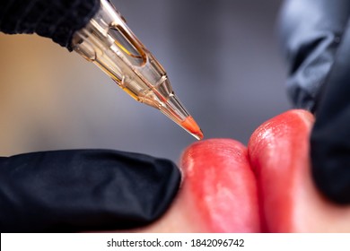 Macro photo of process of applying permanent makeup tattoo of red on lips woman.