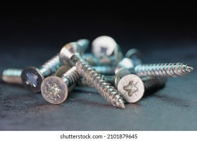 Macro photo of Screws in a pile - selective focus, shallow depth of field, dark background with cool blue light