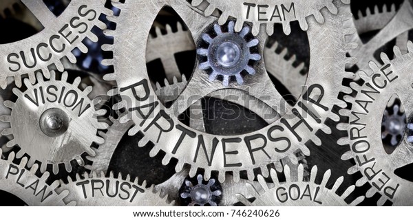 Macro photo of tooth wheel\
mechanism with Partnership related words imprinted on metal\
surface