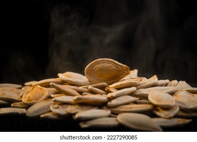 Macro photography with hot tikva seeds. Pumpkin seeds on a black background. Seeds with smoke.