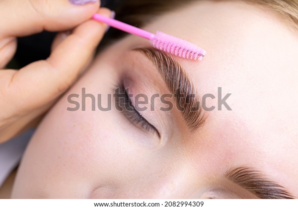 macro photography of the model\'s hairs the\
master combs the eyebrow hairs with a pink brush after the\
procedure long-term styling and\
lamination