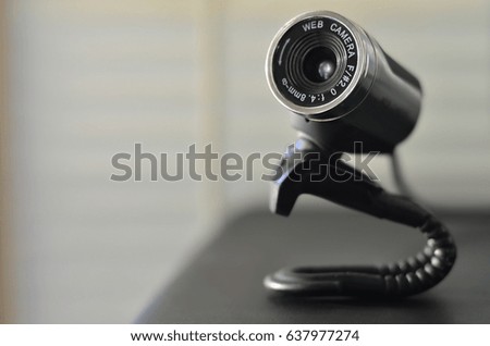Macro photography of a wired web camera for stationary computers and laptops. A web camera image of a cylindrical shape lying on the computer surface. Focus on the camera lens